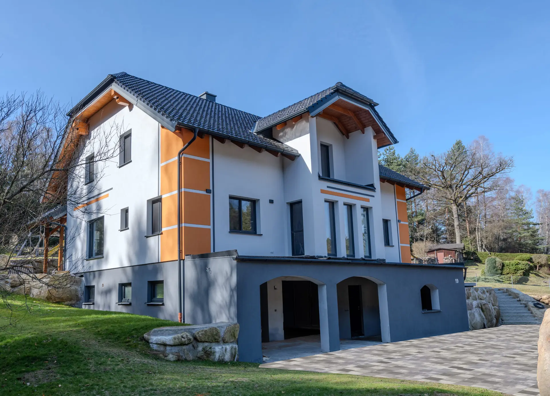 Haus mit unterbrochenen orangenen Eckstreifen sowie grauen und orangenen Balken